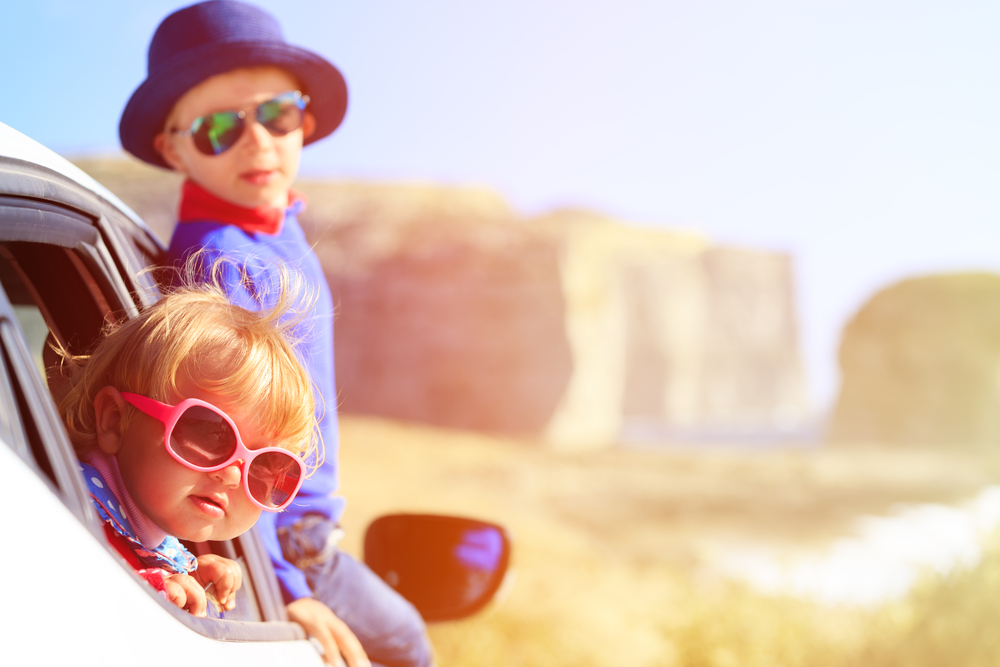 Deux enfants en voiture avec des lunettes de soleil