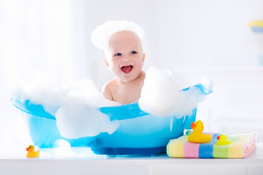 un bébé joue dans son bain moussant dans une petite baignoire